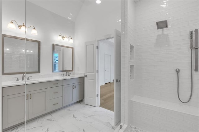 bathroom featuring vanity, lofted ceiling, and a tile shower