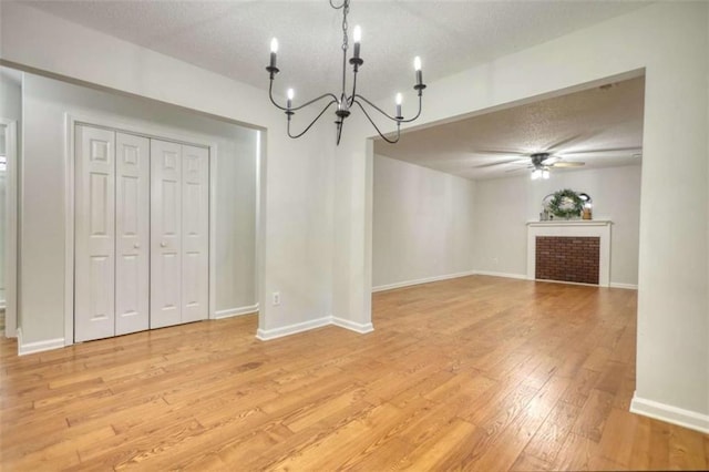 unfurnished dining area featuring ceiling fan with notable chandelier, light hardwood / wood-style floors, and a textured ceiling