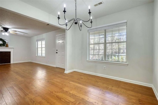 unfurnished dining area with plenty of natural light, wood-type flooring, and ceiling fan with notable chandelier