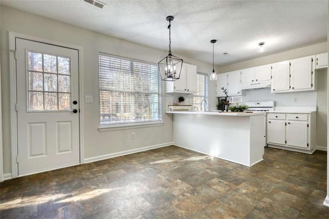 kitchen with white cabinets, sink, hanging light fixtures, a textured ceiling, and kitchen peninsula