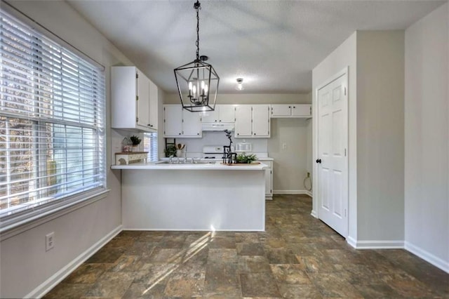 kitchen with a wealth of natural light, white cabinetry, and hanging light fixtures