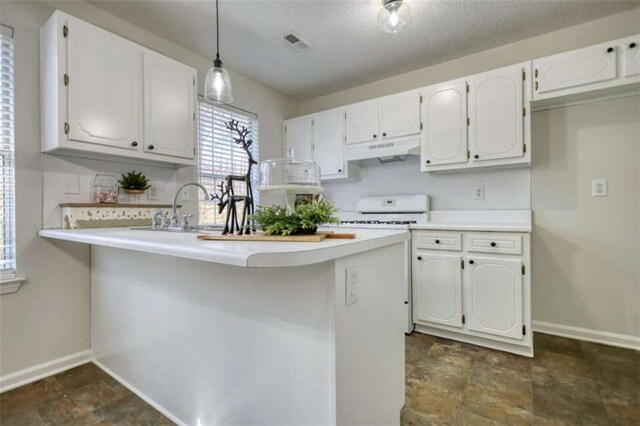 kitchen featuring sink, kitchen peninsula, stove, pendant lighting, and white cabinets