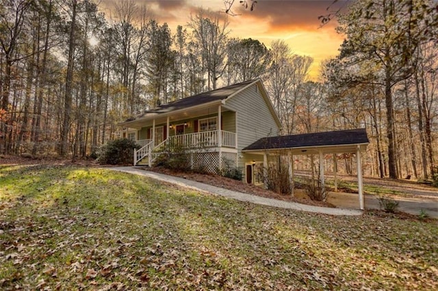 property exterior at dusk with a porch and a yard