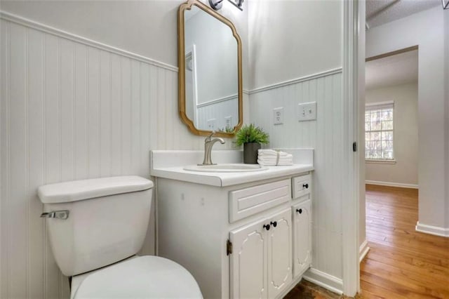 bathroom featuring hardwood / wood-style floors, vanity, wood walls, and toilet