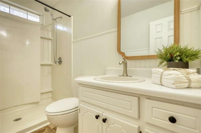 bathroom featuring tiled shower, vanity, and toilet