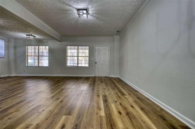 empty room with wood-type flooring, a textured ceiling, and ornamental molding