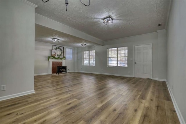 unfurnished living room with wood-type flooring, a textured ceiling, and a brick fireplace