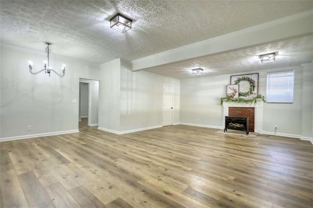 unfurnished living room with ornamental molding, a textured ceiling, hardwood / wood-style flooring, a notable chandelier, and a fireplace