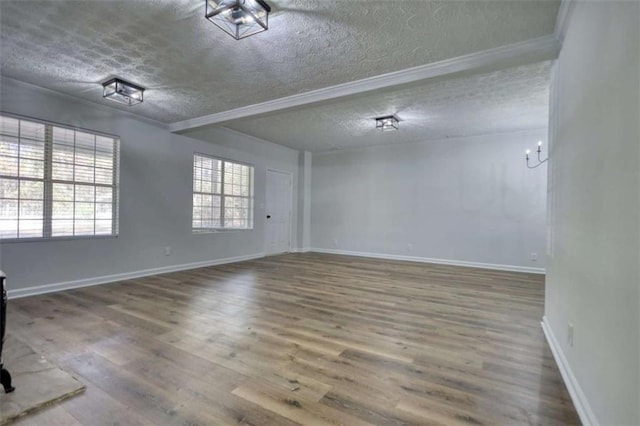 empty room featuring hardwood / wood-style floors, a textured ceiling, and ornamental molding