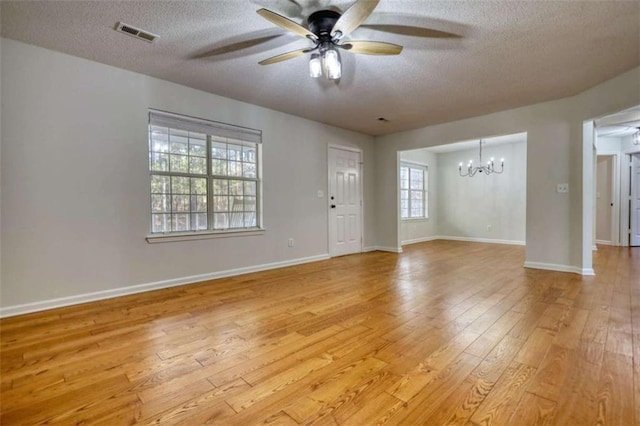 spare room featuring ceiling fan with notable chandelier, light hardwood / wood-style floors, and a textured ceiling