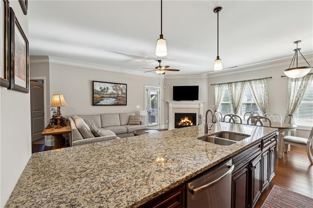 kitchen featuring light stone counters, sink, pendant lighting, and dishwasher