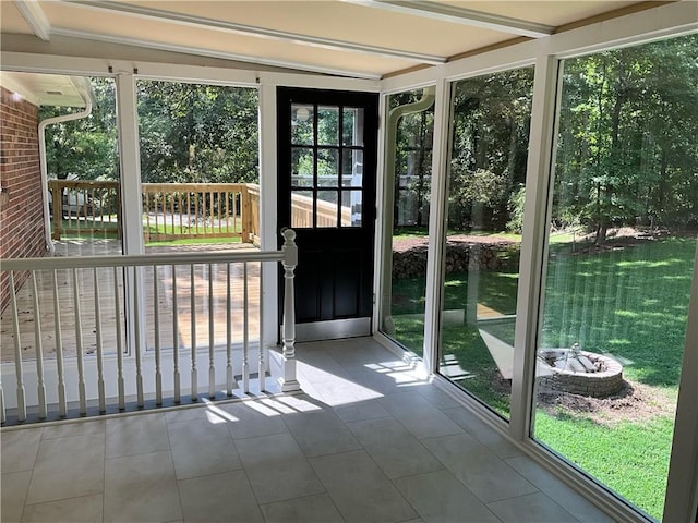 unfurnished sunroom featuring beam ceiling