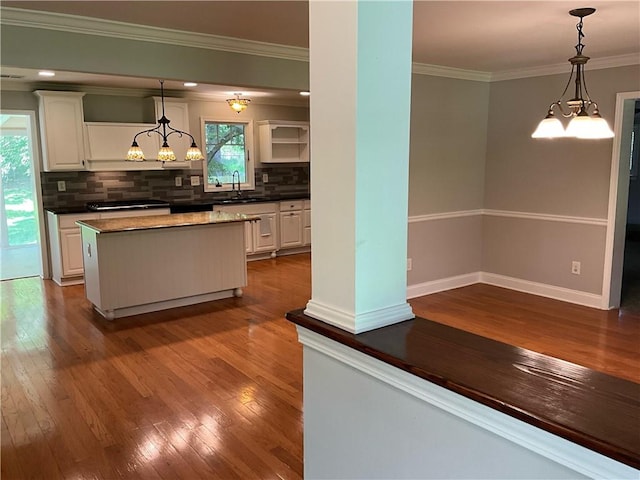 kitchen featuring hanging light fixtures, a kitchen island, hardwood / wood-style flooring, and white cabinetry