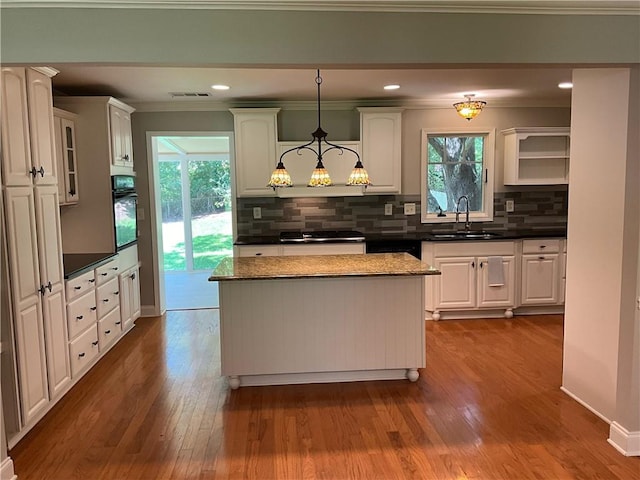 kitchen with a healthy amount of sunlight, decorative light fixtures, oven, and sink