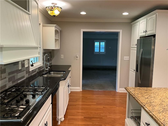 kitchen featuring white cabinets, sink, stainless steel appliances, light wood-type flooring, and decorative backsplash