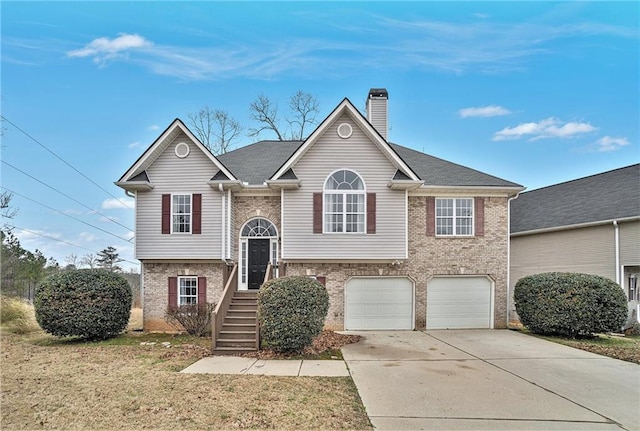 bi-level home featuring driveway, a garage, a chimney, and brick siding