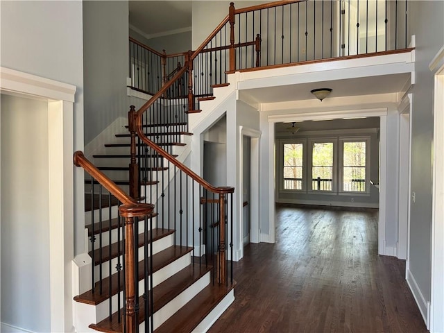 entryway with baseboards, a high ceiling, wood finished floors, and crown molding