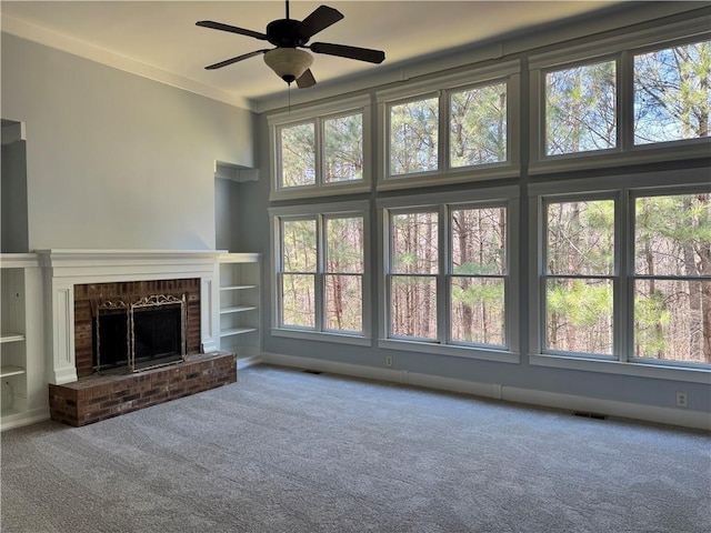 unfurnished living room featuring carpet floors, a wealth of natural light, visible vents, and a fireplace