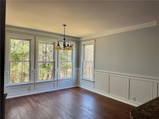 unfurnished dining area with dark wood-style floors, wainscoting, visible vents, and an inviting chandelier