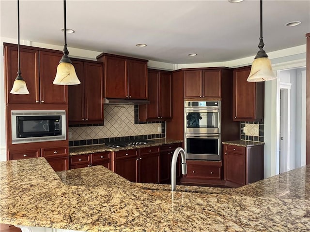 kitchen with black microwave, stainless steel double oven, under cabinet range hood, gas stovetop, and backsplash