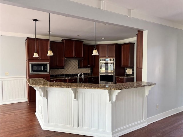 kitchen with double oven, dark stone countertops, dark wood finished floors, and built in microwave