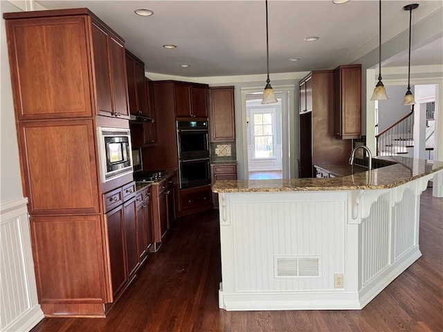 kitchen featuring stone counters, a breakfast bar, double wall oven, built in microwave, and a peninsula