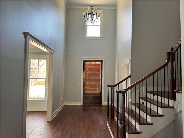 foyer entrance with baseboards, plenty of natural light, a high ceiling, and wood finished floors