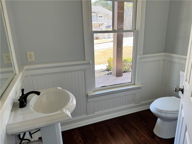 half bath featuring a wainscoted wall, wood finished floors, and toilet