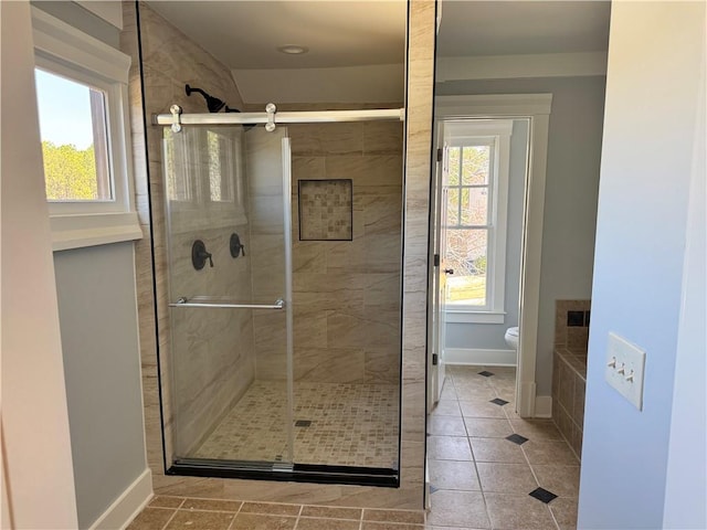 full bathroom featuring a wealth of natural light, a stall shower, and toilet