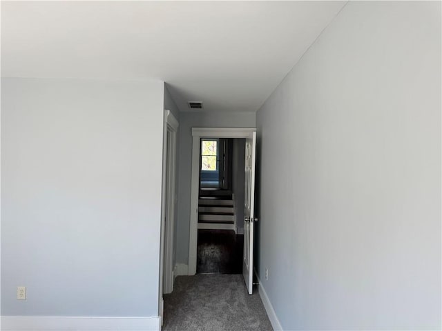 hallway featuring carpet floors, visible vents, and baseboards