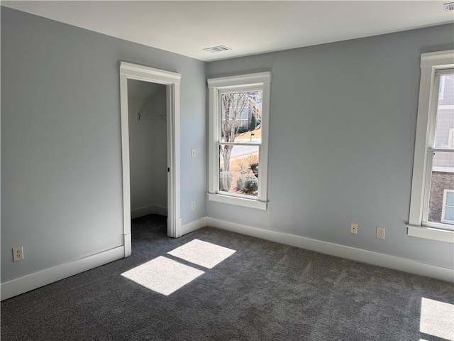 unfurnished bedroom with a walk in closet, a closet, visible vents, carpet flooring, and baseboards