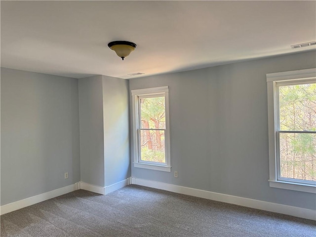 carpeted empty room with a wealth of natural light, visible vents, and baseboards