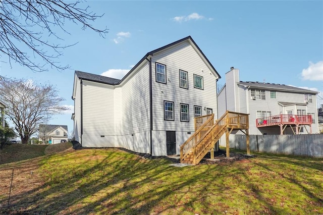 rear view of house featuring a wooden deck and a yard