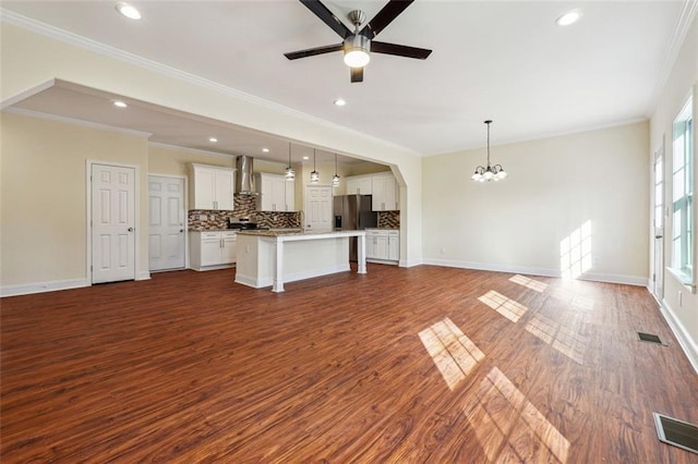 unfurnished living room featuring ceiling fan with notable chandelier, dark wood-type flooring, and crown molding