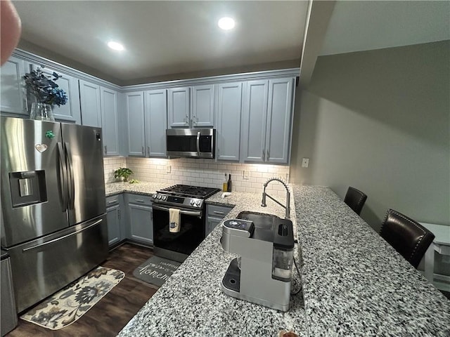 127 Spring Way Sq, Canton, GA 30114 - kitchen featuring appliances with stainless steel finishes, light stone countertops, dark wood finished floors, decorative backsplash, and gray cabinetry