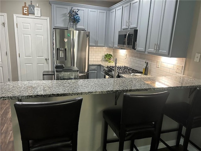 127 Spring Way Sq, Canton, GA 30114 - kitchen with appliances with stainless steel finishes, gray cabinetry, light stone countertops, and backsplash