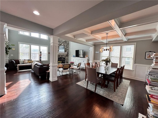 dining space with beam ceiling, a fireplace, plenty of natural light, decorative columns, and dark wood-type flooring