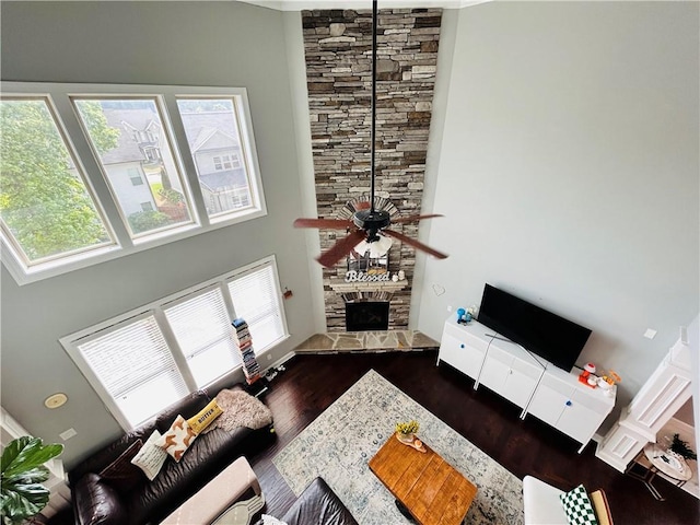 living area featuring ceiling fan, wood finished floors, a high ceiling, and a fireplace