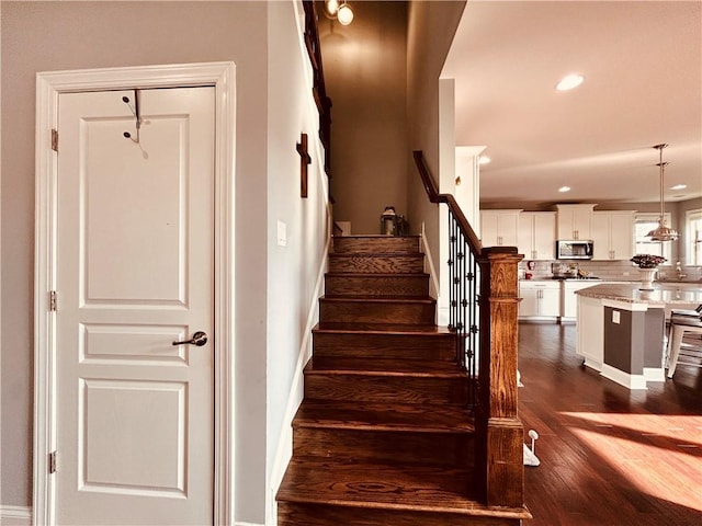 stairs with baseboards, recessed lighting, and wood finished floors