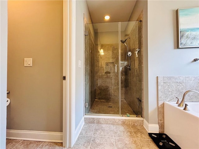 bathroom with baseboards, tile patterned floors, a bath, and a shower stall