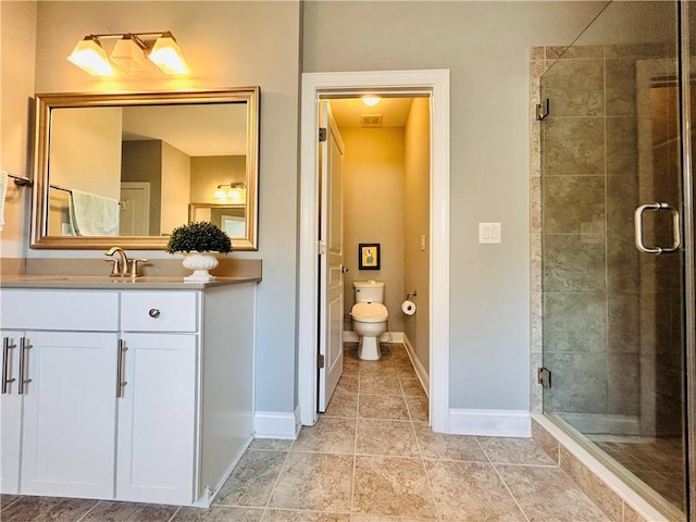 full bath with vanity, baseboards, a shower stall, and toilet