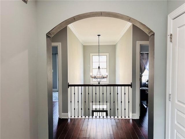 hallway with an inviting chandelier, arched walkways, ornamental molding, and hardwood / wood-style flooring