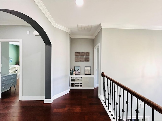 hall with crown molding, arched walkways, and wood finished floors