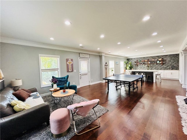 recreation room with crown molding, a fireplace, recessed lighting, decorative columns, and dark wood-type flooring