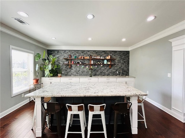 bar with backsplash, crown molding, visible vents, and dark wood-style floors
