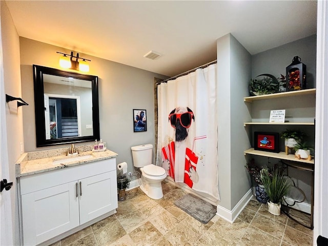bathroom with visible vents, vanity, toilet, baseboards, and stone finish floor