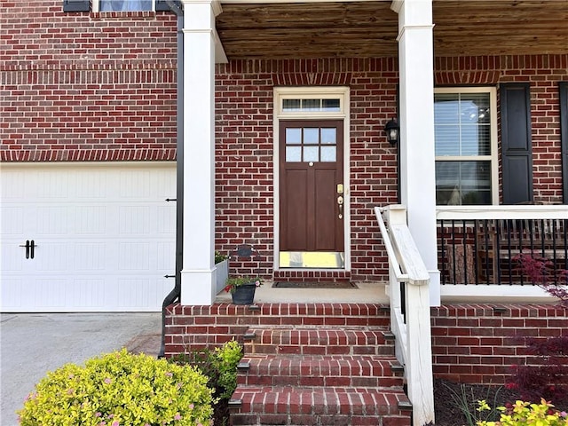 property entrance featuring covered porch, brick siding, an attached garage, and driveway