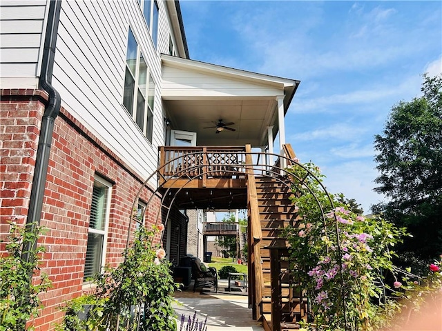 view of home's exterior with stairway, brick siding, and a ceiling fan