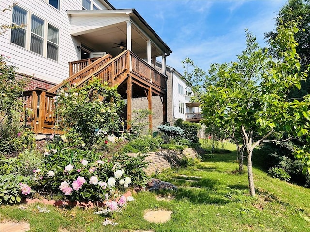 view of side of home with stairs, ceiling fan, a lawn, and a porch