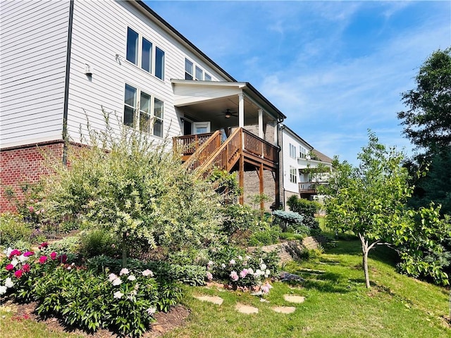 exterior space featuring a lawn, ceiling fan, and stairs